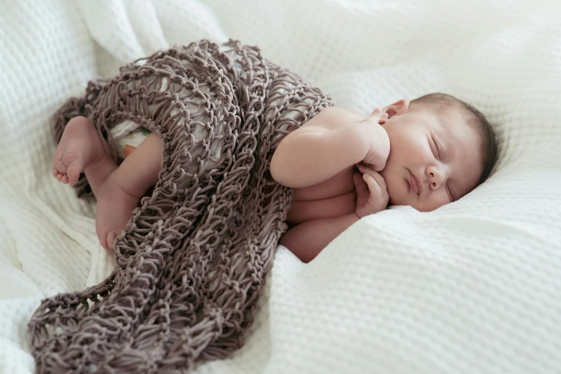 Pasgeboren baby onder gebreide deken